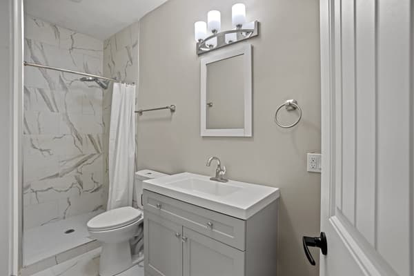 Bathroom with a marble-look tiled shower and a grey vanity at 203 Colborne Street, Kingston