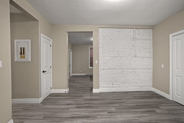 Entry looking down the hall past a whitewashed brick wall at 203 Colborne Street, Kingston