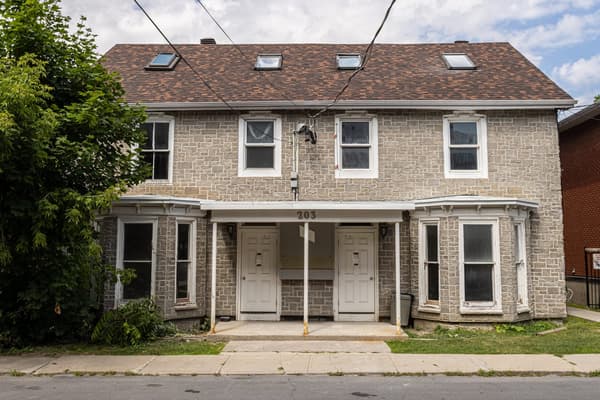 Heritage stone exterior with bay windows and a covered front porch at 203 Colborne Street, Kingston