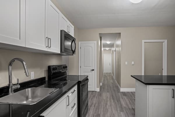 Galley kitchen looking down the hallway to the suite door at 203 Colborne Street, Kingston