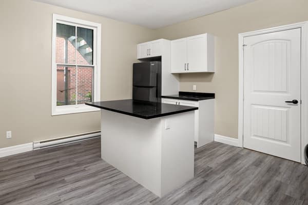 Kitchen island and refrigerator beneath a tall window at 203 Colborne Street, Kingston