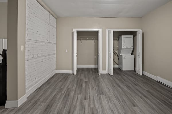 Double closets and a stacked washer and dryer beside the brick wall at 203 Colborne Street, Kingston
