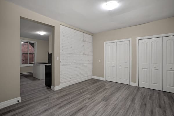 Living room with a whitewashed brick feature wall, open to the kitchen at 203 Colborne Street, Kingston